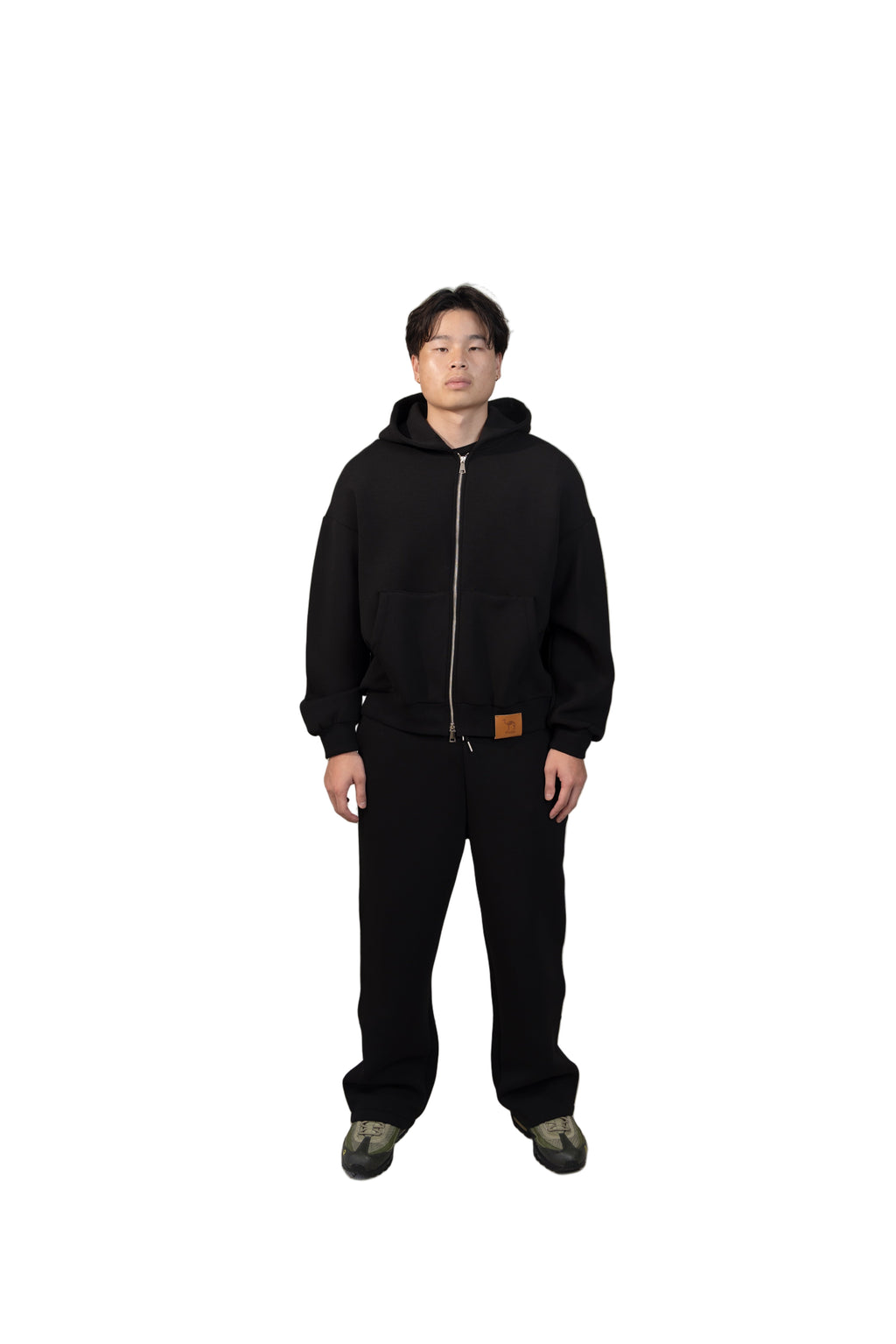 Person wearing a black outfit standing in a modern living room.