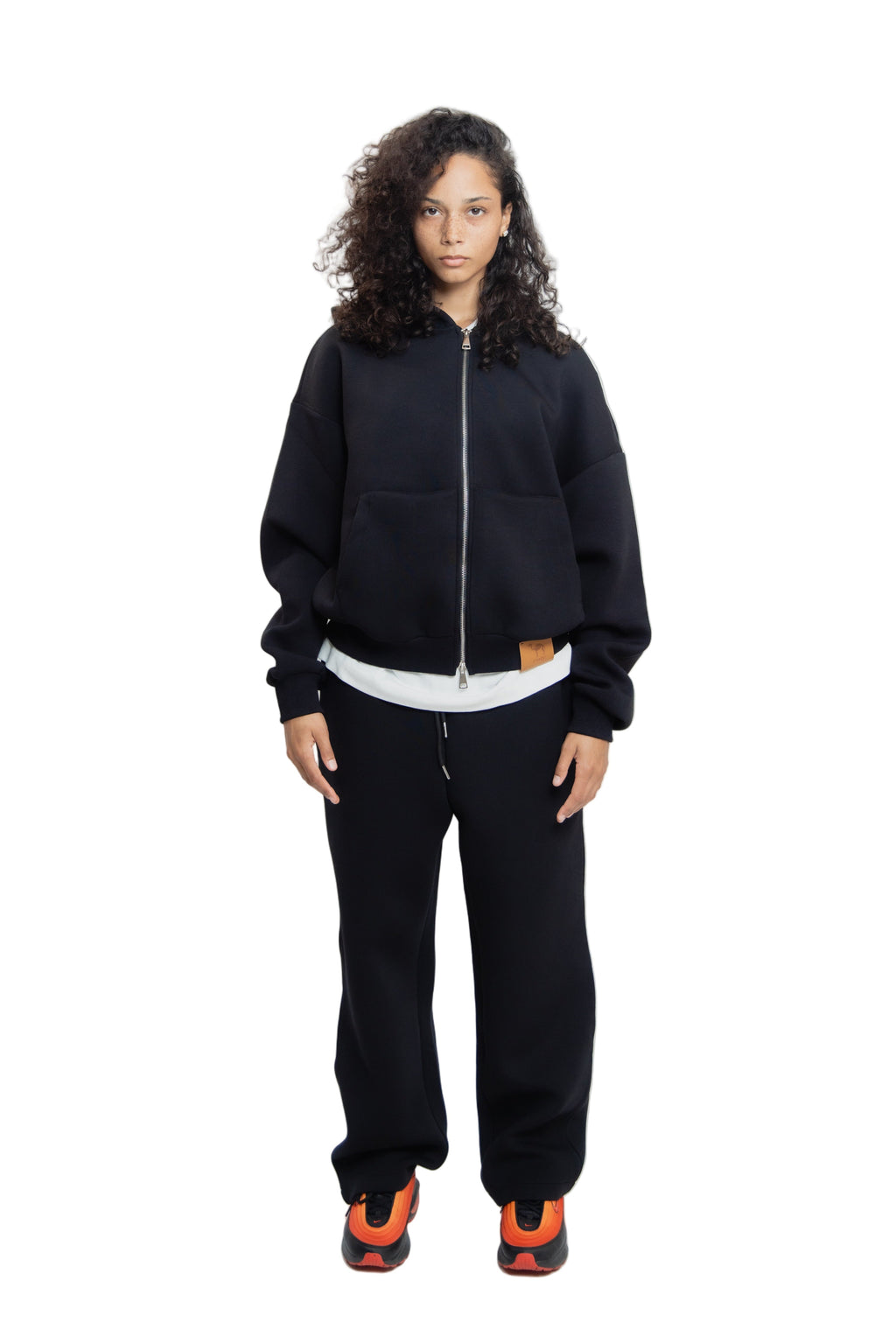 Person wearing a black tracksuit with white shirt on a white background