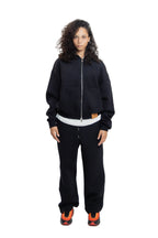 Person wearing a black tracksuit with white shirt on a white background