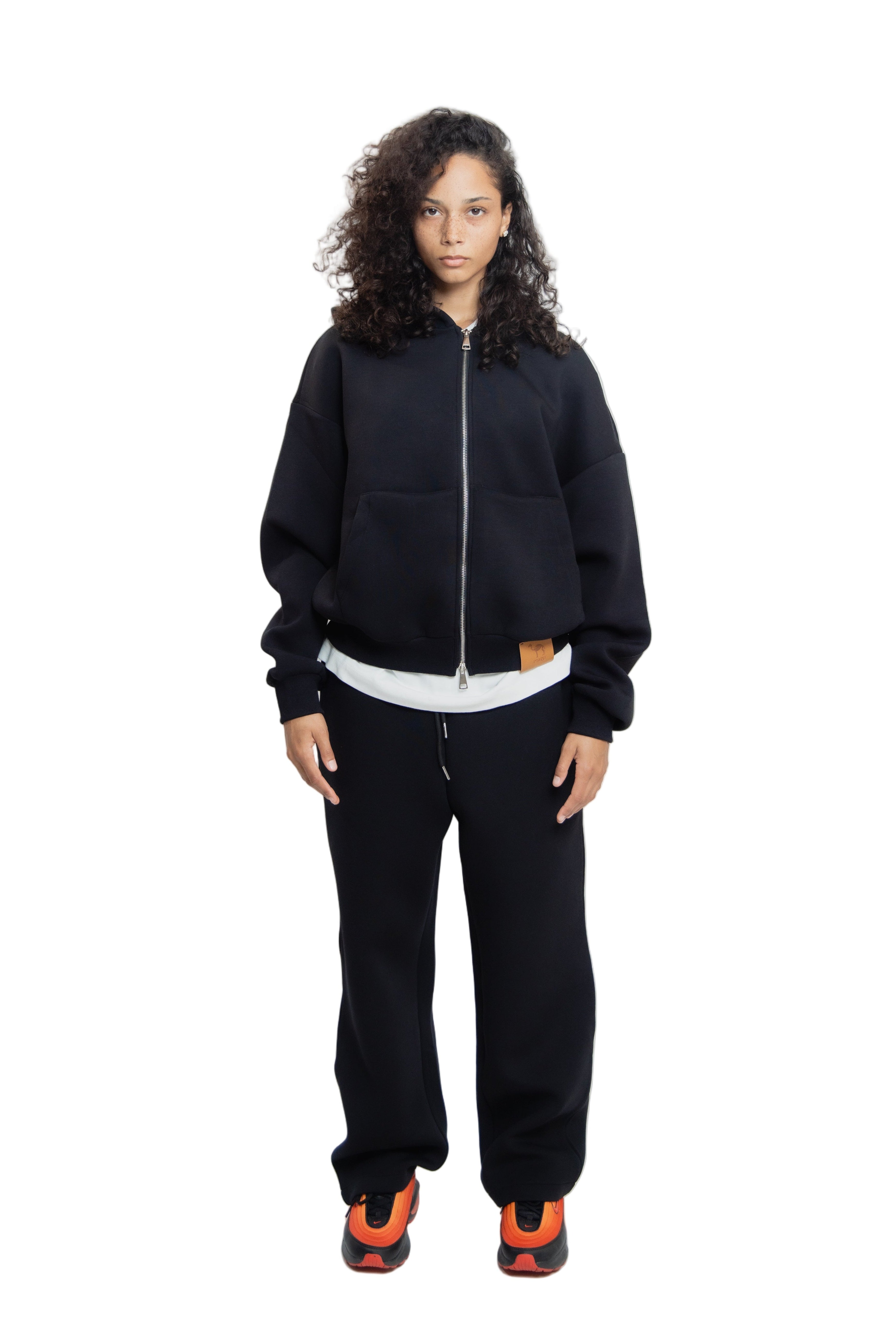 Person wearing a black tracksuit with white shirt on a white background