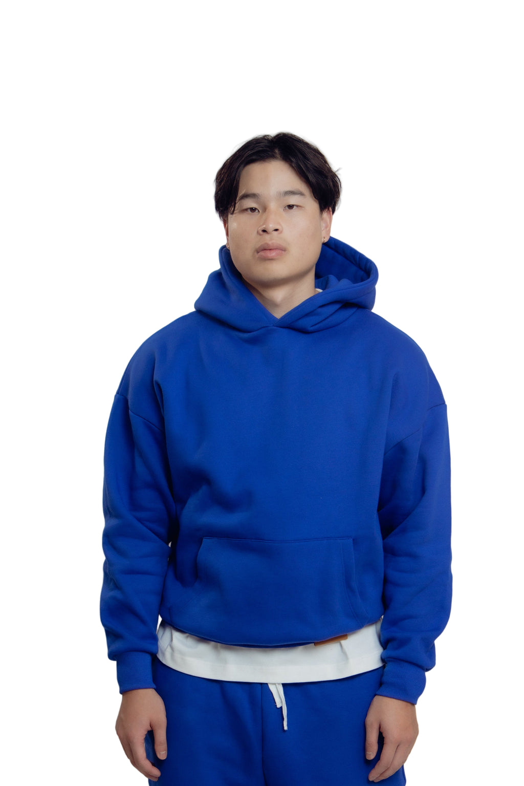 Person wearing a blue hoodie and pants on a white background