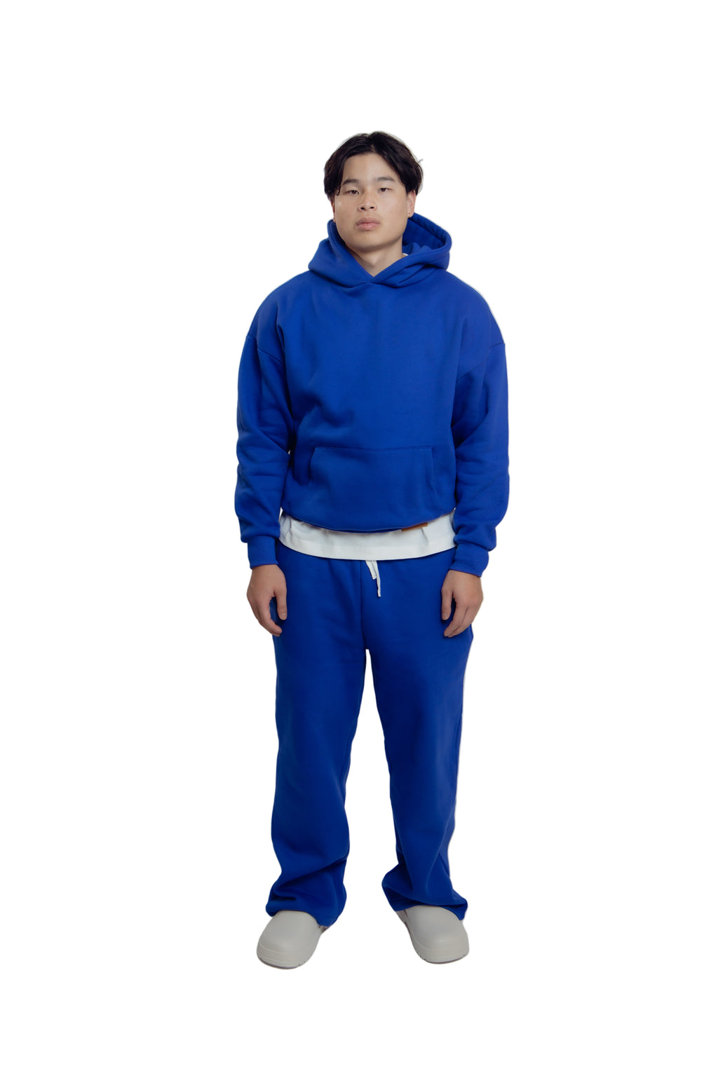 Person wearing a blue hoodie and pants on a white background