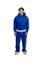 Person wearing a blue hoodie and pants on a white background
